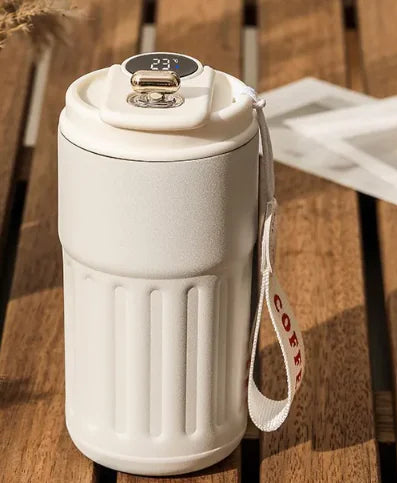 Smart digital thermal bottle in white with LED temperature display on wooden surface.